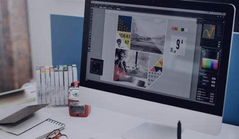 Computer monitor displaying design software with a desk and stationery items in the background