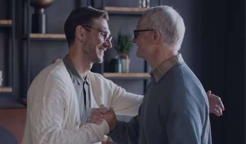 Two men shaking hands in a professional setting with shelves in the background